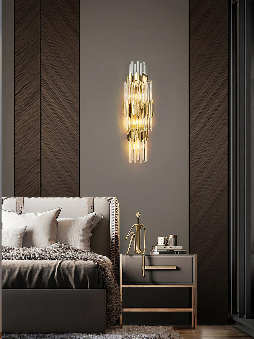 The sconce lit on a wood herringbone wall above a bed with gray pillows
