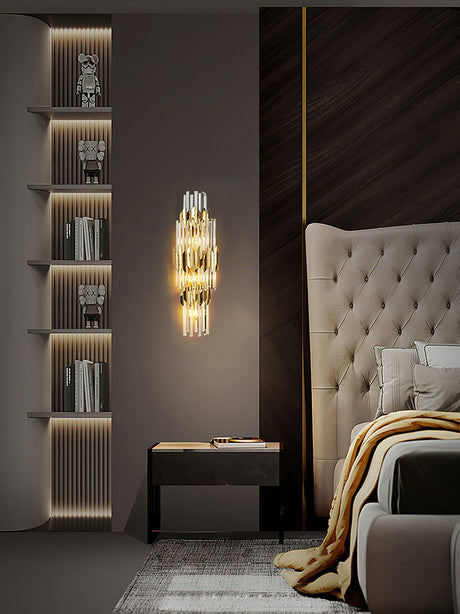 The sconce beside a tufted headboard and a wall of lit shelves