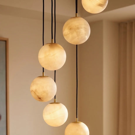 Lit alabaster spheres at four different heights beside a pale curtain