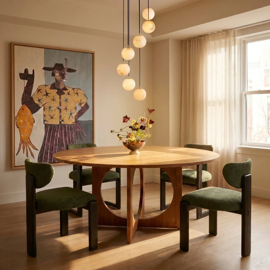 Lit spheres cascading beside a round dining table with green chairs and a window