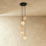 Five lit stone spheres dropping at different lengths from a black plate