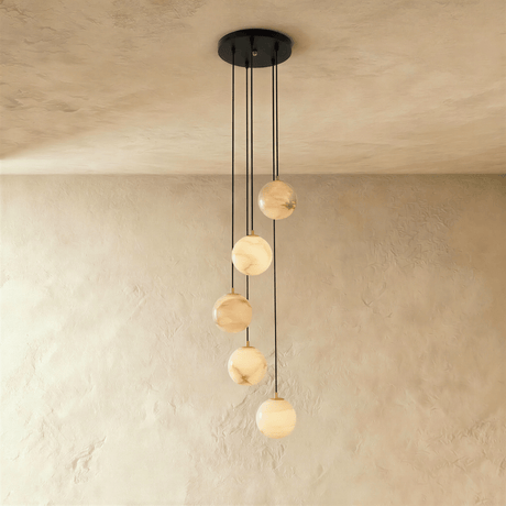Five lit stone spheres dropping at different lengths from a black plate
