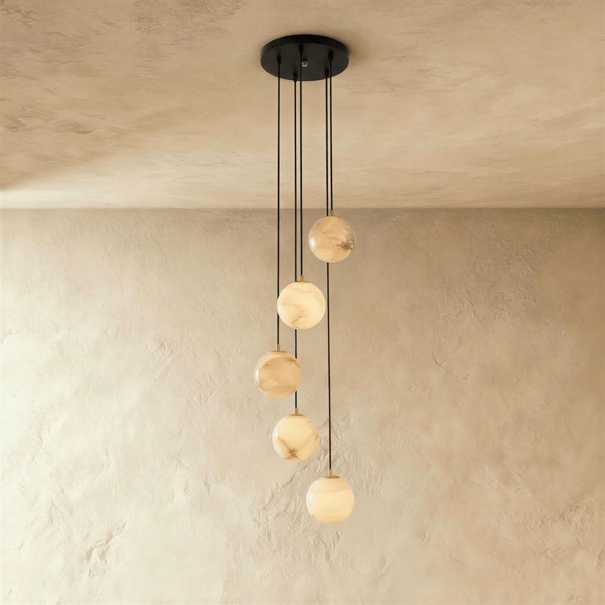 Five lit stone spheres dropping at different lengths from a black plate