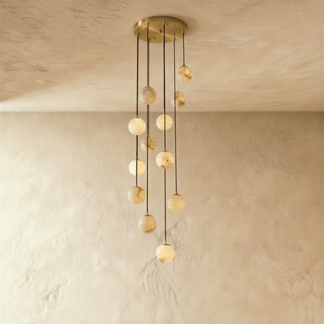 Nine lit stone spheres dropping at different lengths from a brass plate
