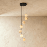 Seven lit alabaster spheres spread down a plaster wall on black cords