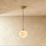One lit alabaster sphere on a cord below a small brass ceiling plate