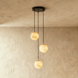 Three lit alabaster spheres at stepped heights on black cords