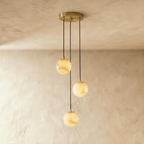 Three lit alabaster spheres hung from a round brass ceiling plate