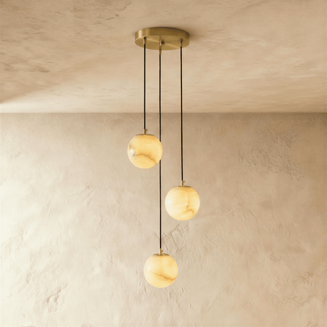 Three lit alabaster spheres hung from a round brass ceiling plate