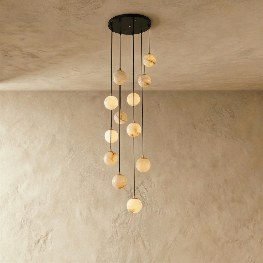 Twelve lit alabaster spheres cascading on black cords from a round black plate