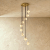 Twelve lit alabaster spheres in a cascade below a wide brass plate