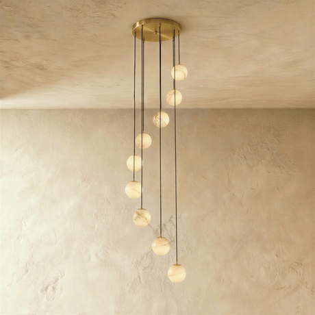 Twelve lit alabaster spheres in a cascade below a wide brass plate