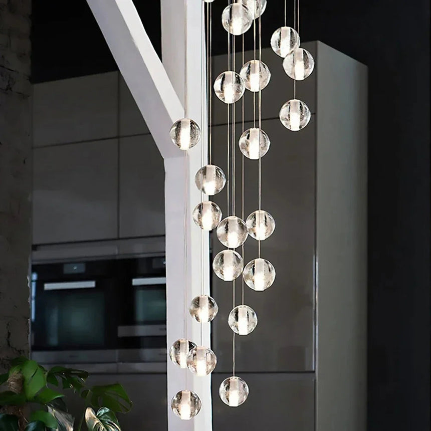 A tall column of clear spheres dropping through a white double height void