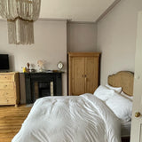Hung in a bedroom above a white bed with a fireplace and a wardrobe behind
