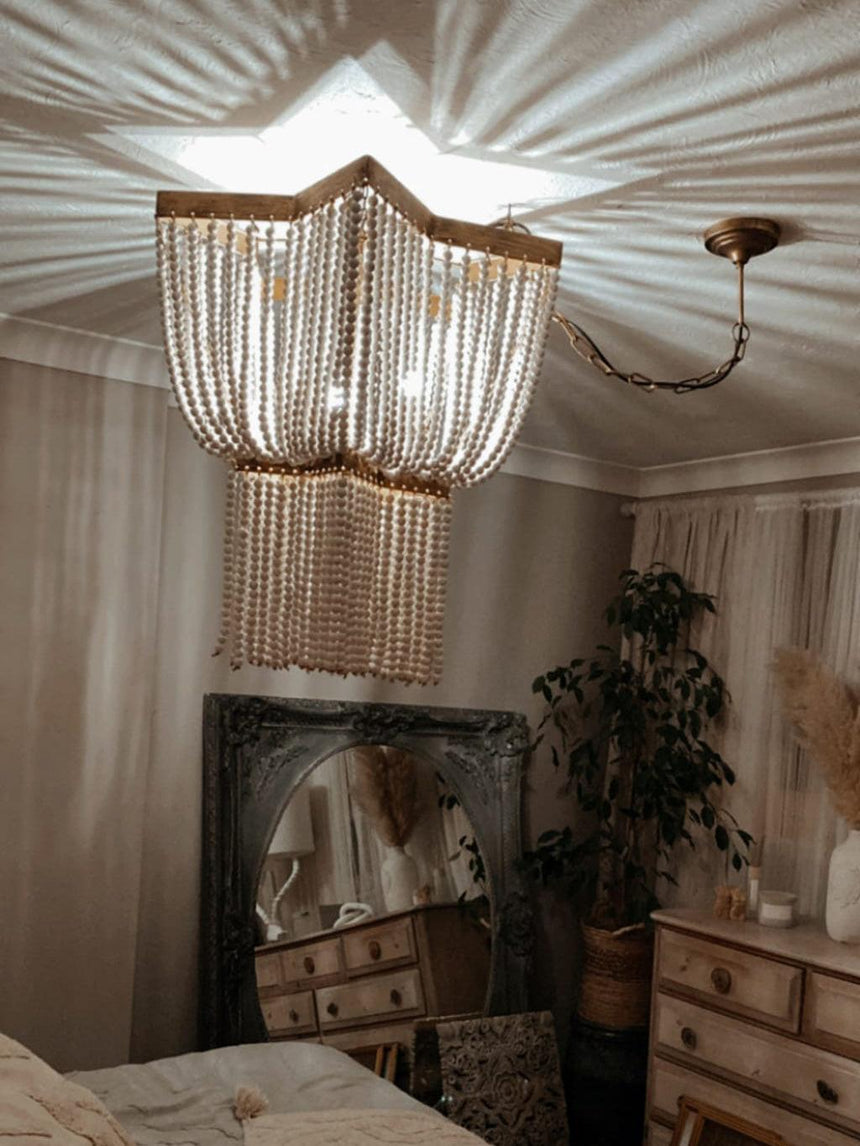 Lit above a bed beside a leaning mirror, a dresser and a tall plant