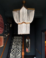 Lit in a dark hall above a doorway with a patterned stair runner beyond
