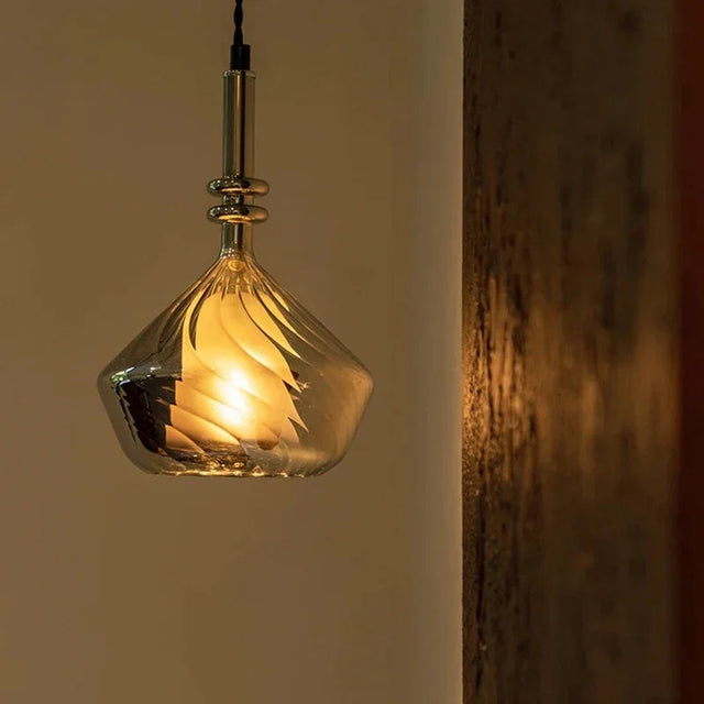 An amber faceted glass pendant lit in front of a shelf of books