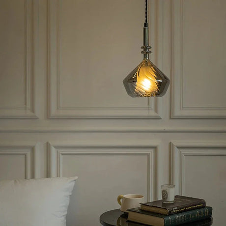 The faceted shade lit against a paneled wall above a console and vase