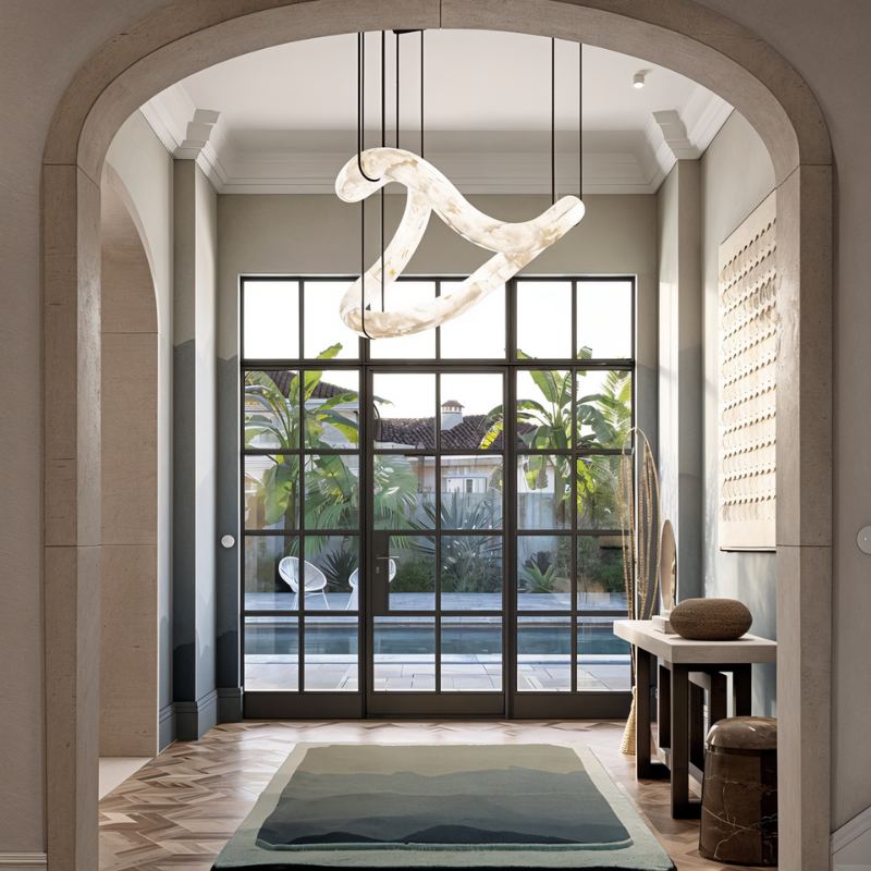 The lit stone tube in an entrance hall under an arch, with a rug and a window