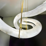 The curve of the alabaster tube where a brass cable meets the stone