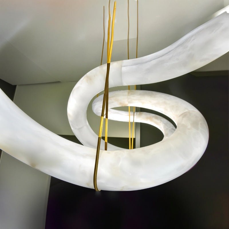 The curve of the alabaster tube where a brass cable meets the stone