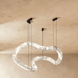 One winding alabaster tube lit, hung on four cables from a plaster ceiling