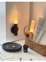 Lit beside a woven basket of books with a small tray and a candle nearby
