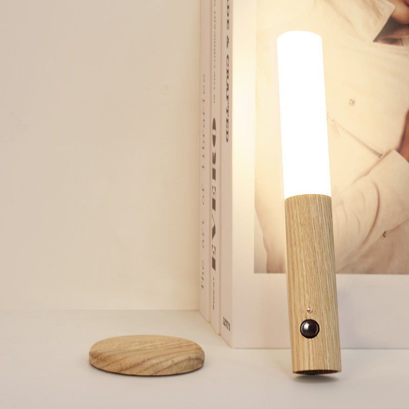 Lit upright against a bookshelf edge, the frosted tube glowing warm on wood