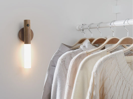 Lit inside a wardrobe cabinet above a rail of white shirts on wooden hangers