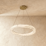 The ring in pale alabaster hung on cables against a plaster ceiling