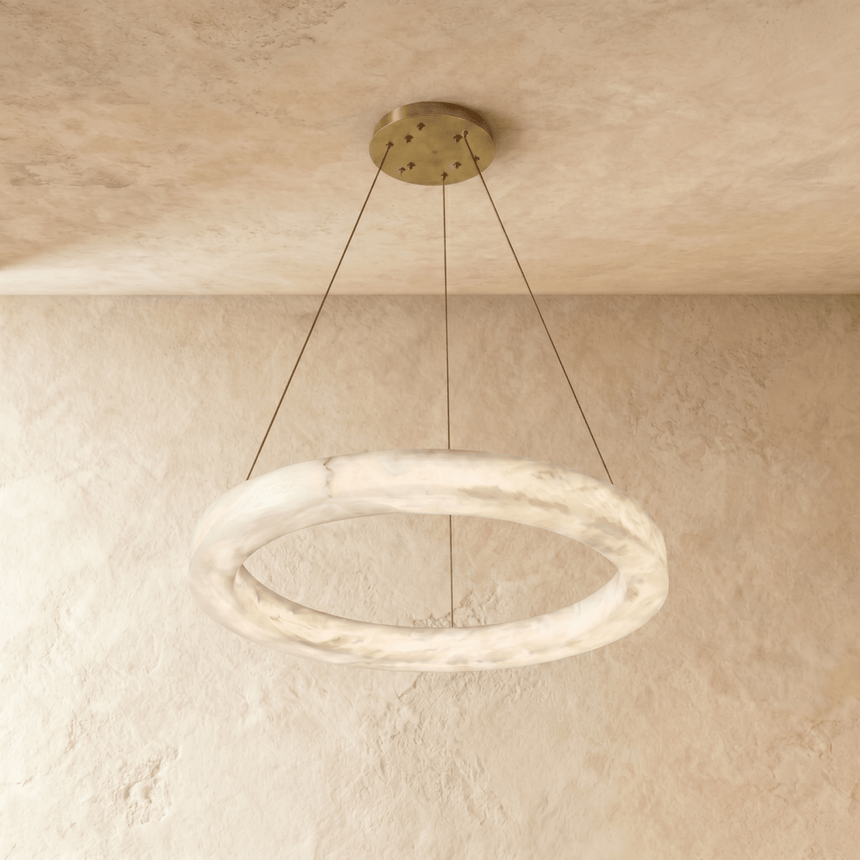 The ring in pale alabaster hung on cables against a plaster ceiling