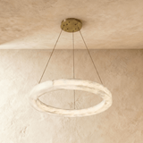 A smaller alabaster ring on three cables below a round brass plate