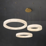 Three alabaster rings at staggered heights against a dark background