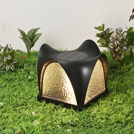 Two petal caps lit on a lawn with shrubs and a path behind them