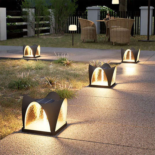 Lit petal caps along a garden path beside planters and a timber fence