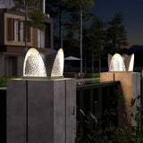 Two petal caps lit on pillars with a garden umbrella and chairs behind