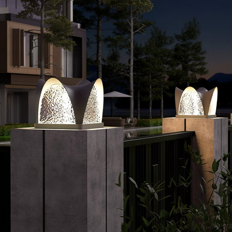 Two petal caps lit on pillars with a garden umbrella and chairs behind