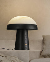 Stone table lamp with a black base lit on a plaster ledge