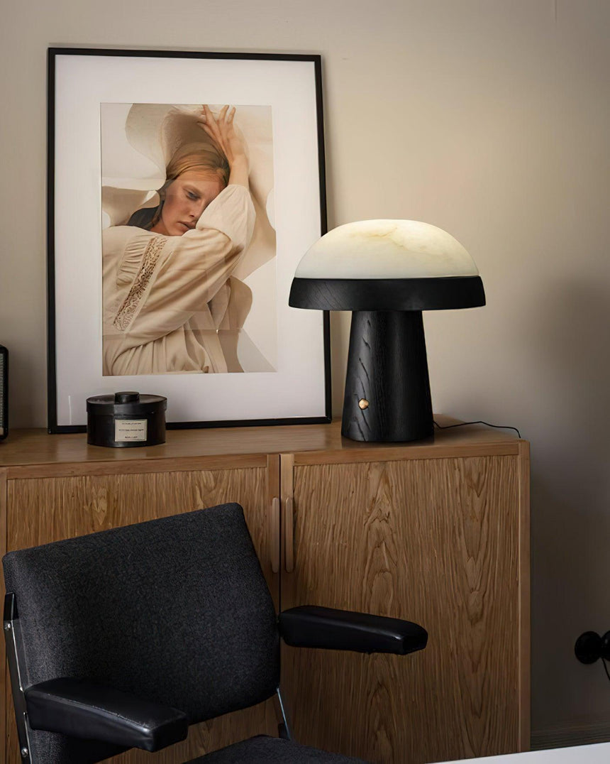 Stone table lamp with a black base on a sideboard beside a print