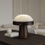 Stone table lamp lit on a dark coffee table in a pale living room