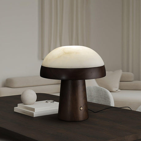 Stone table lamp lit on a dark coffee table in a pale living room