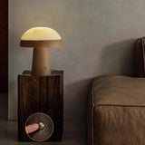 Stone table lamp lit on a dark wood plinth beside a leather sofa