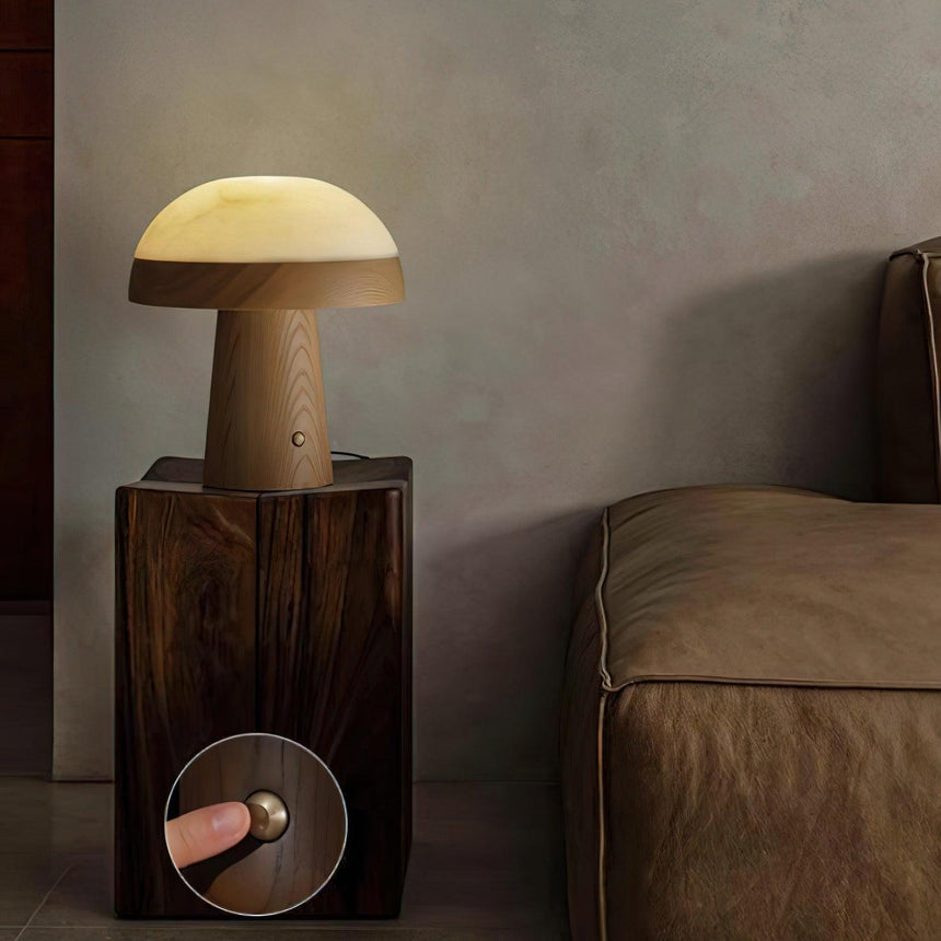 Stone table lamp lit on a dark wood plinth beside a leather sofa