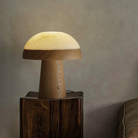 Stone table lamp lit on a rough wood block against a plaster wall