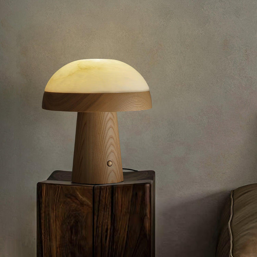 Stone table lamp lit on a rough wood block against a plaster wall