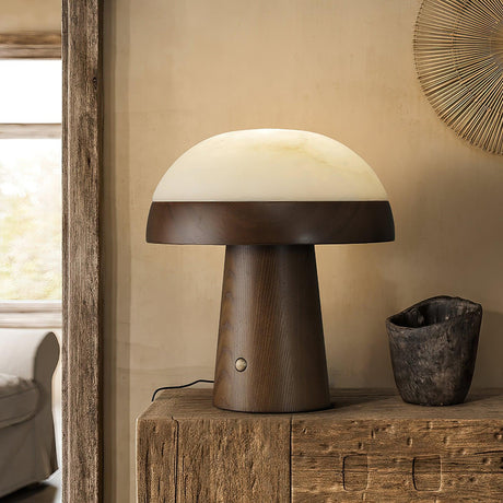 Stone table lamp in walnut lit on a rustic console by a window