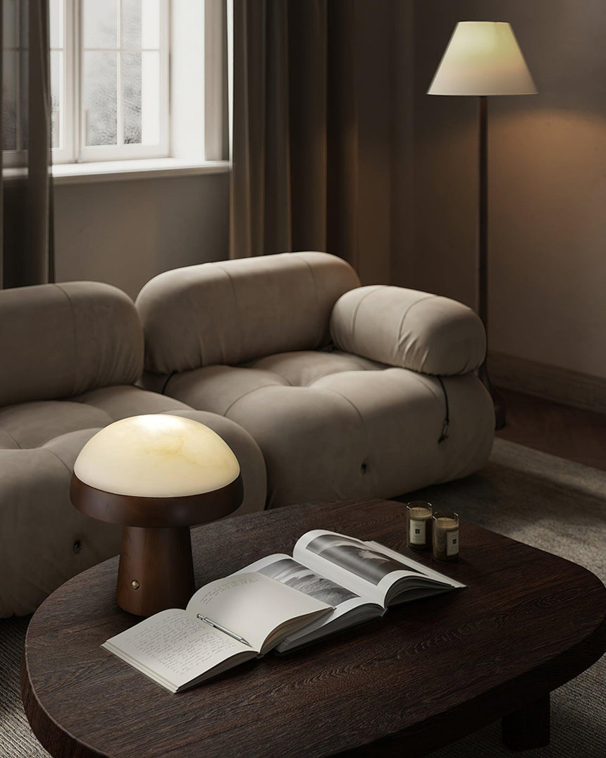Stone table lamp lit on a coffee table beside an open magazine