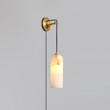 The brass version lit, hanging on a plain gray wall