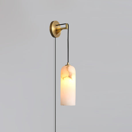 The brass version lit, hanging on a plain gray wall