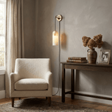 The lit lamp beside a curtain above a console with vases and books